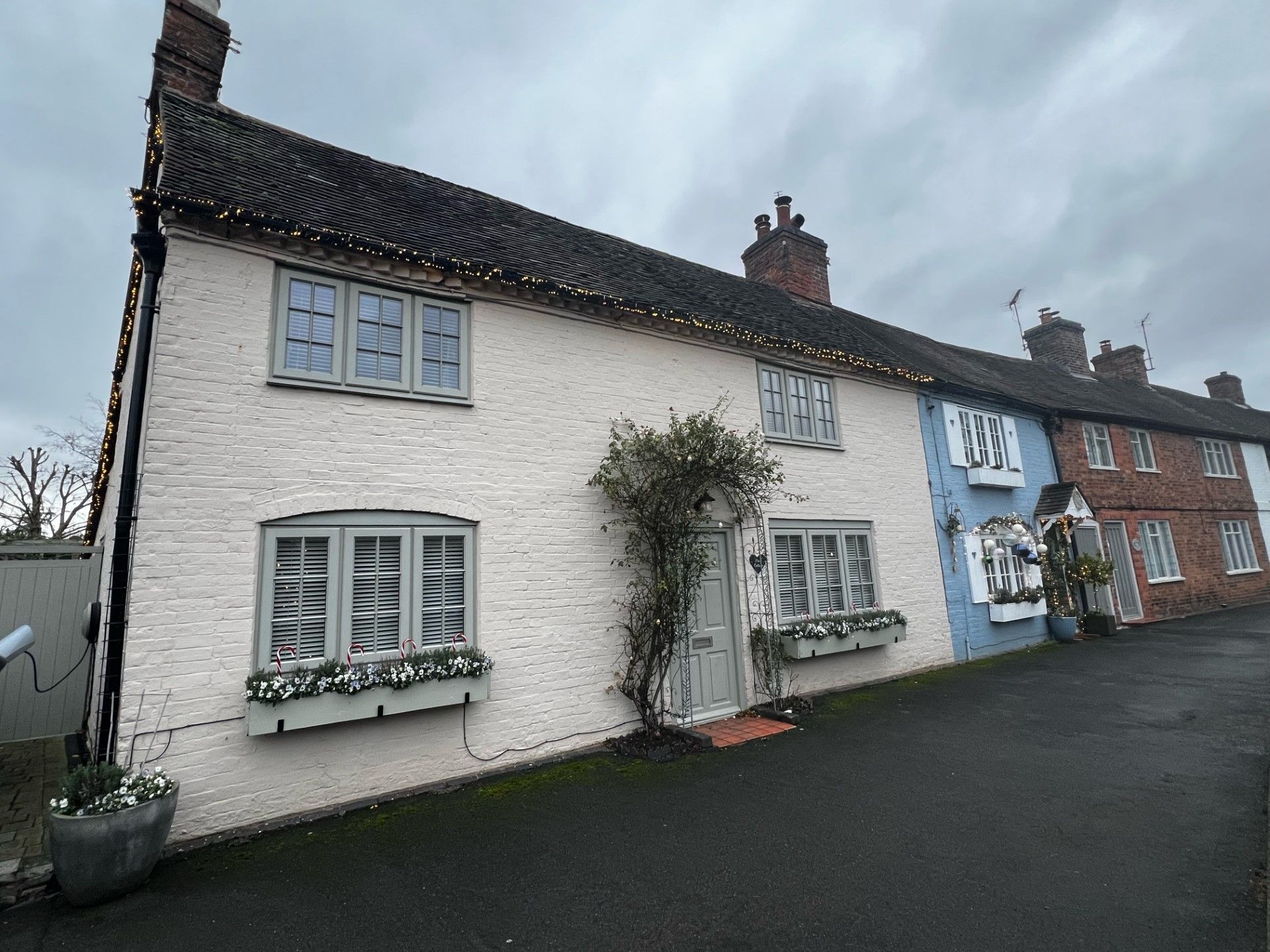 Row of colorful cottages on a cloudy day, one white, one blue, and others brick.