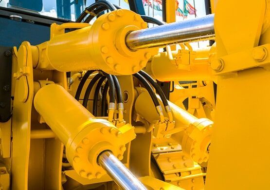 A close up of a yellow hydraulic system on a bulldozer.