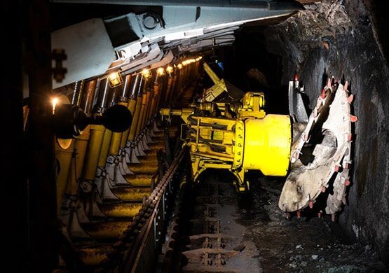 A machine is cutting a hole in the ground in a mine.