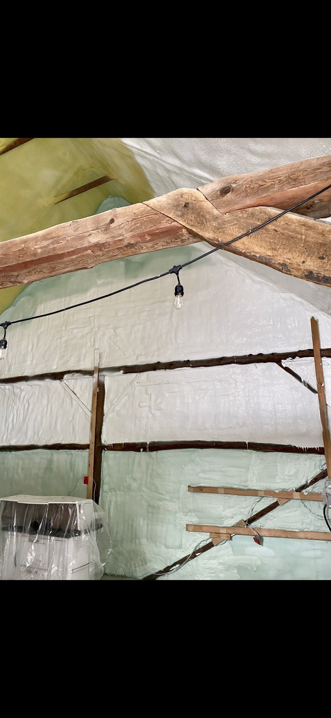 Une scène extérieure avec des poutres en bois, une lumière et une structure recouverte de matériau blanc.