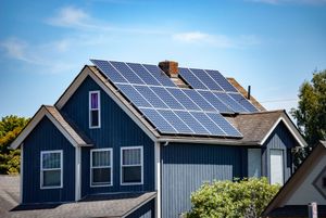 A blue house with solar panels on the roof.