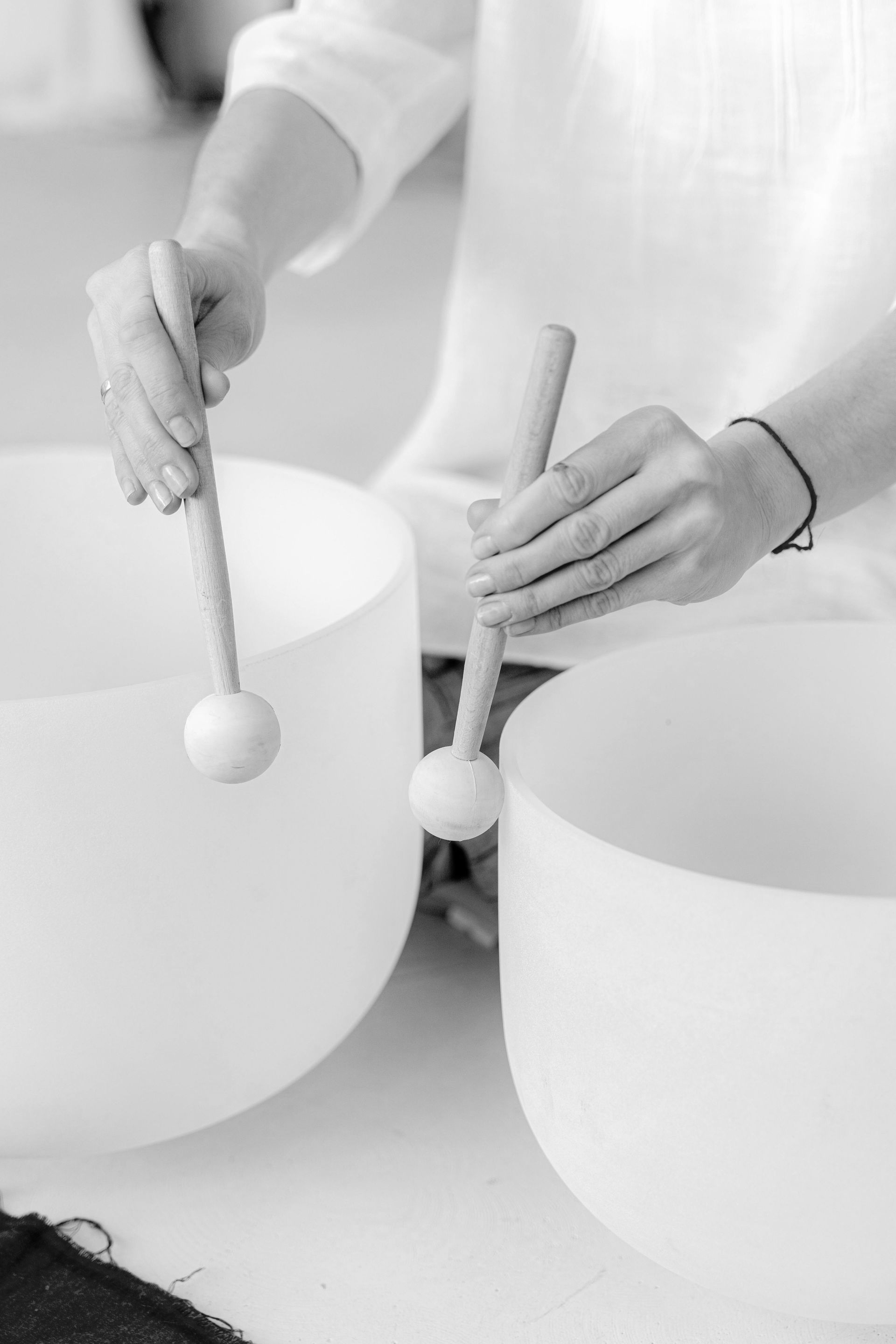Mani che suonano tamburi a percussione con bacchette sferiche bianche su grandi tamburi bianchi