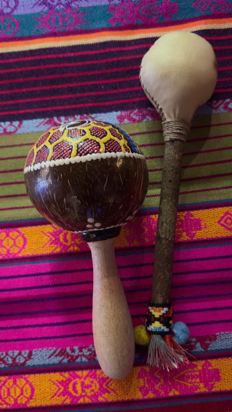 Due strumenti a percussione decorati su uno sfondo di tessuto a righe colorate