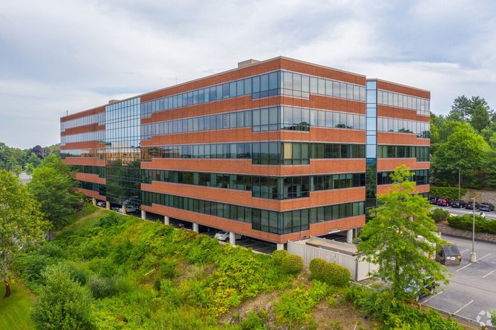 An aerial view of a large brick building surrounded by trees and a parking lot.