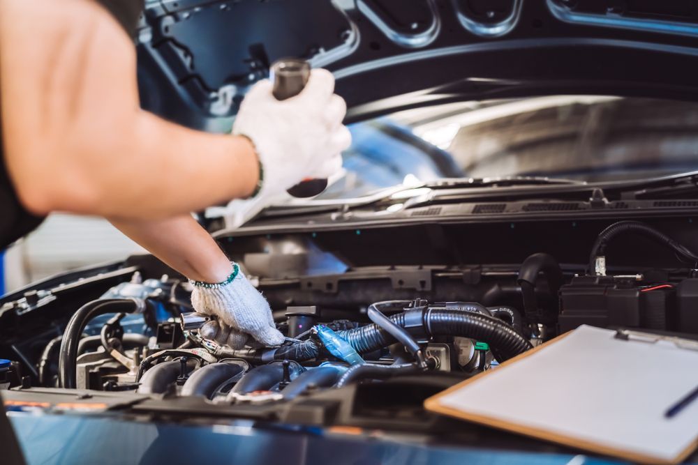 Mechanic Wearing Gloves Checks Engine Components Under An Open Car Hood — Van Diemen's Automotive & Electrical Repairs In Bellerive, TAS