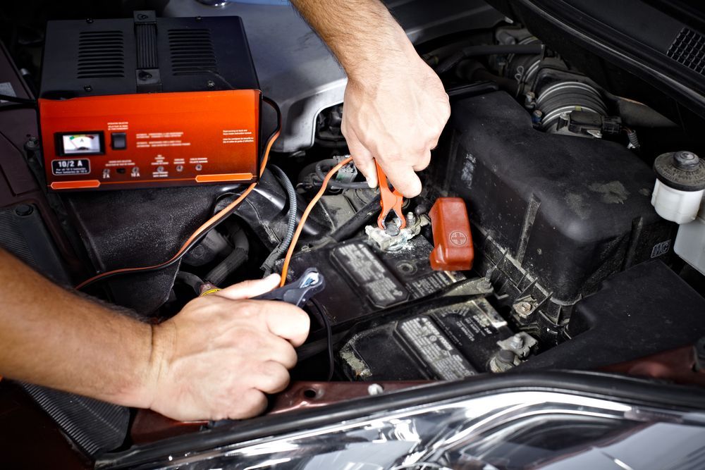 Mechanic Jump-starting a Car Battery With Cables and a Portable Charger in the Engine Bay — Van Diemen's Automotive & Electrical Repairs In Bellerive, TAS