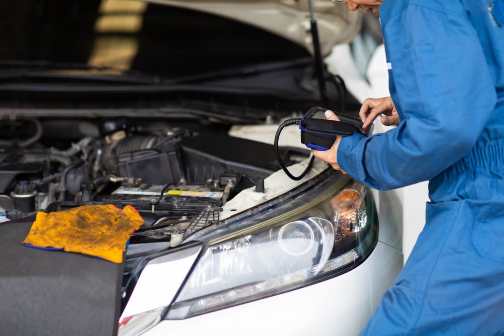 Mechanic Using a Diagnostic Tool on a Car With Its Hood Open in a Garage — Van Diemen's Automotive & Electrical Repairs In Bellerive, TAS