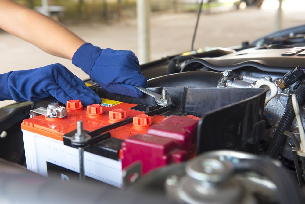 Gloved Hands Connecting Jumper Cables to a Car Battery in an Engine Bay — Van Diemen's Automotive & Electrical Repairs In Bellerive, TAS