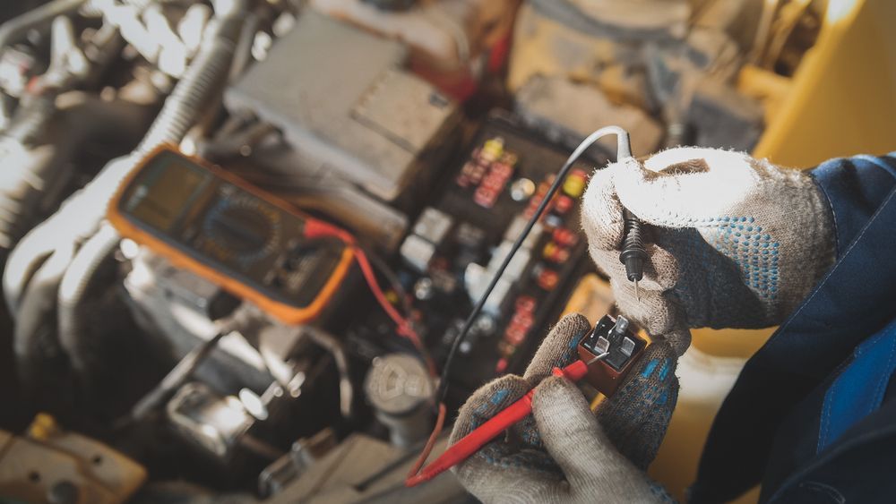 Gloved Hands Using a Multimeter to Inspect Wiring in an Open Car Engine Bay — Van Diemen's Automotive & Electrical Repairs In Bellerive, TAS