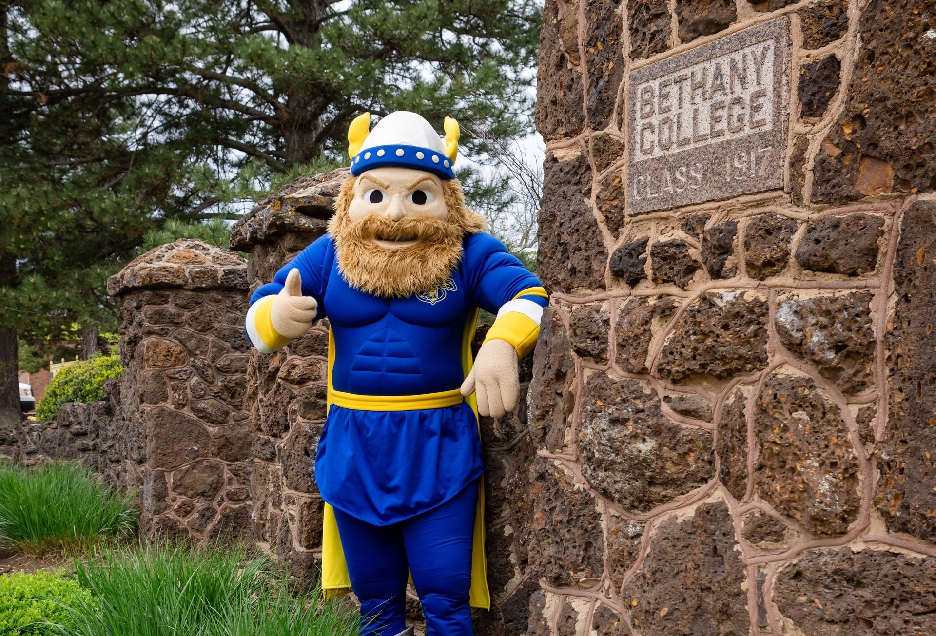 Sven the swede mascot leaning on the Bethany gates.