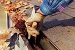 removing leaves from gutters on a house
