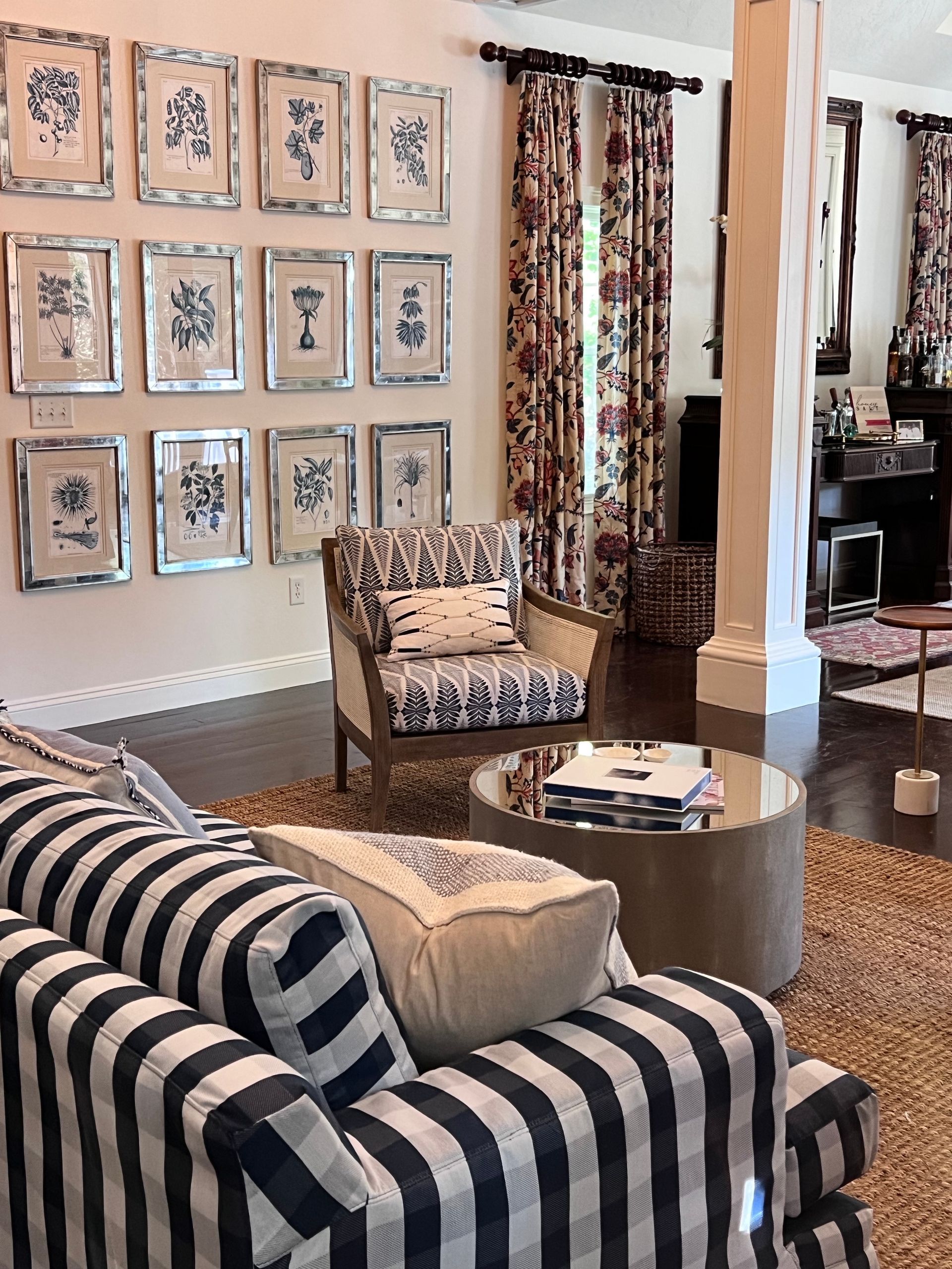 A living room with hardwood floors , a wall of framed prints, a couch and a chair.