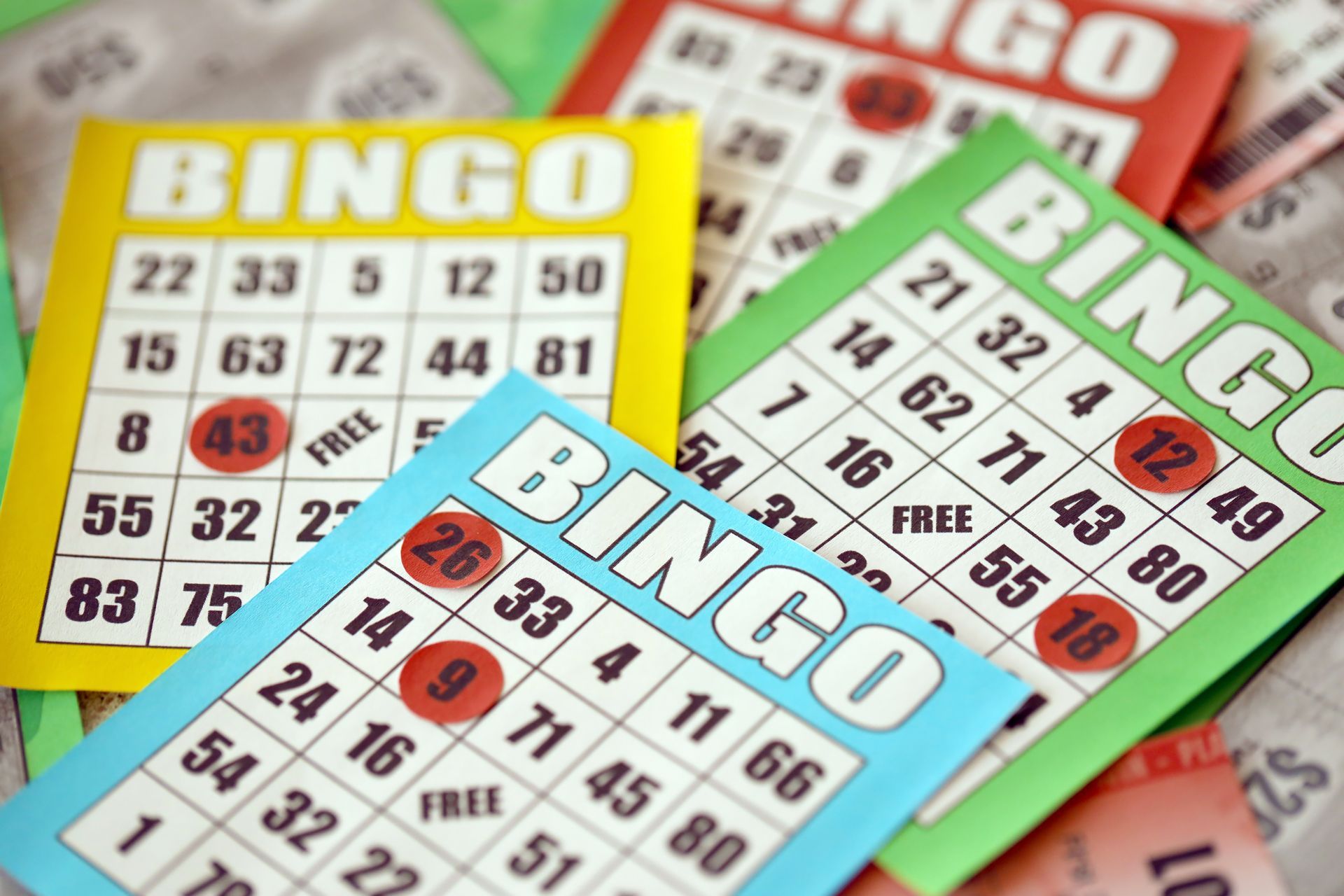Close-up of colorful bingo cards with red markers covering some numbers.