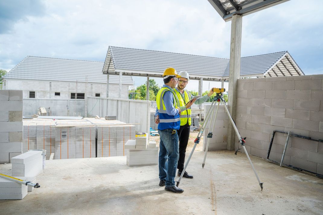Due operai edili sono in piedi in un cantiere e guardano un tablet.