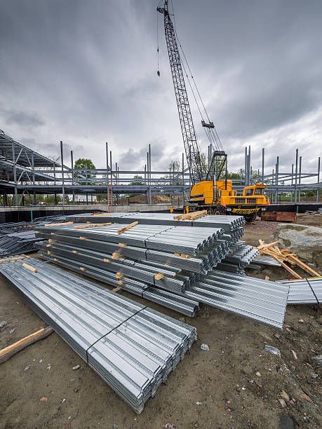 Construction site with metal beams and crane in background, showcasing industrial crane services.