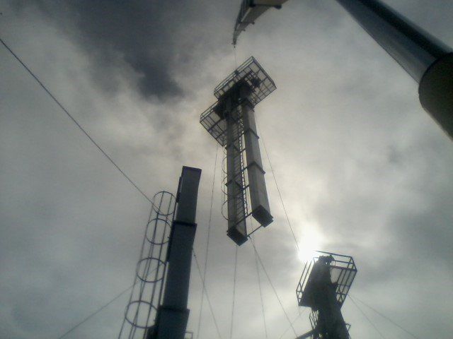 Overhead view of several metal towers against a cloudy sky.