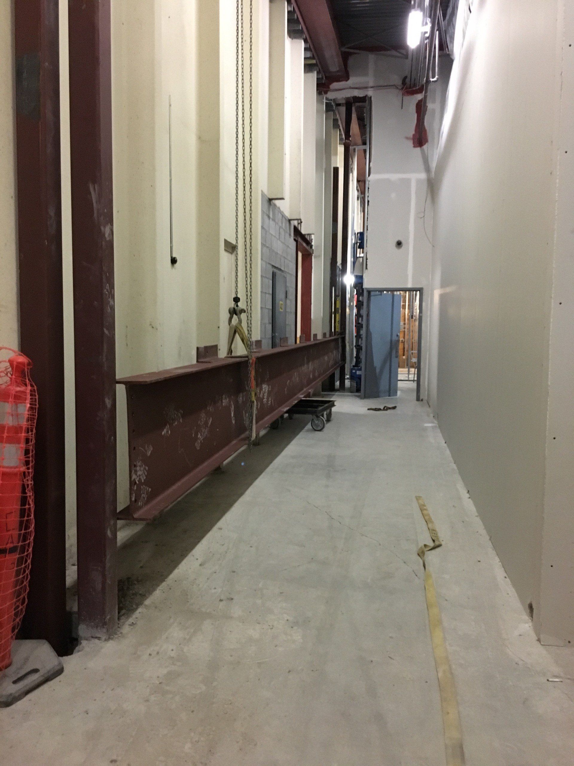 Narrow hallway with large steel beam on a rolling cart. Construction site.