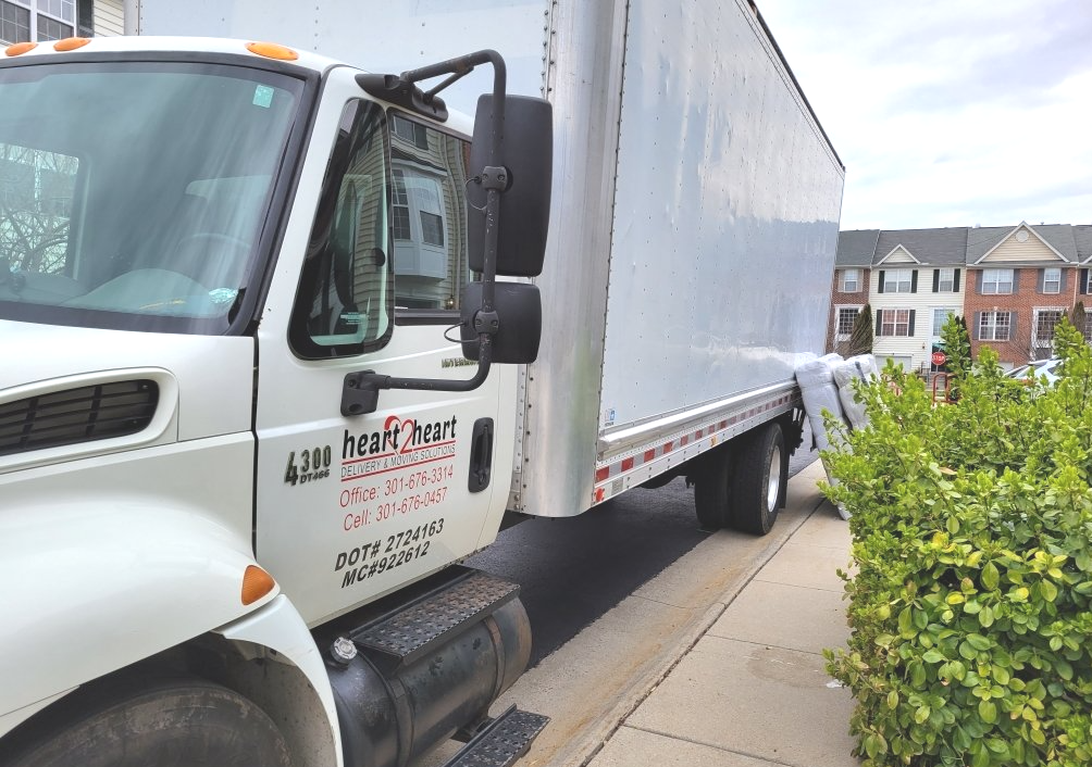 A white moving truck is parked on the side of the road.