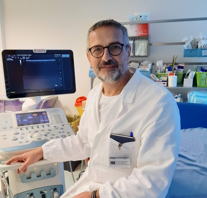 un uomo in camice da laboratorio è seduto davanti a una macchina ad ultrasuoni