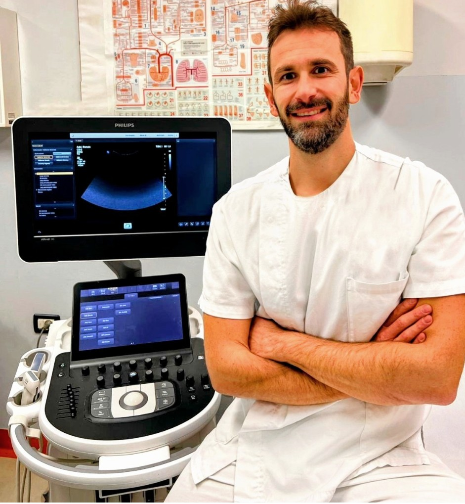 un uomo in camice da laboratorio e cravatta è in piedi con le braccia incrociate.