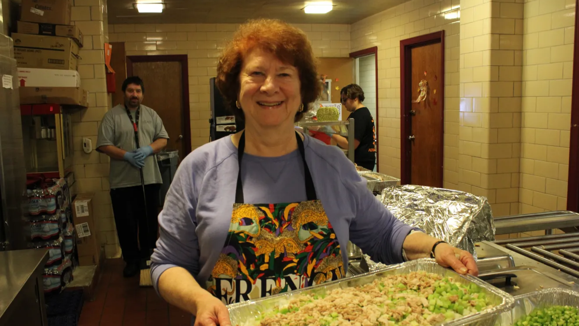Smiling woman holds up tray of salad