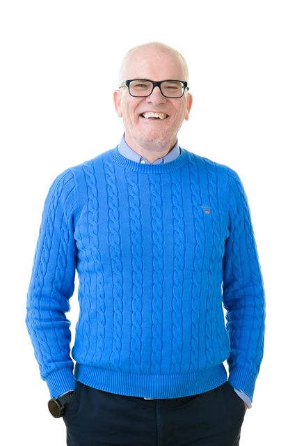 An older man in a blue jumper. 