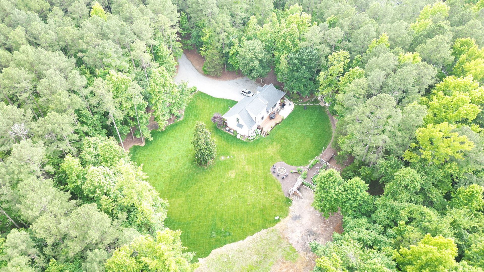 An aerial view of a house in the middle of a forest.