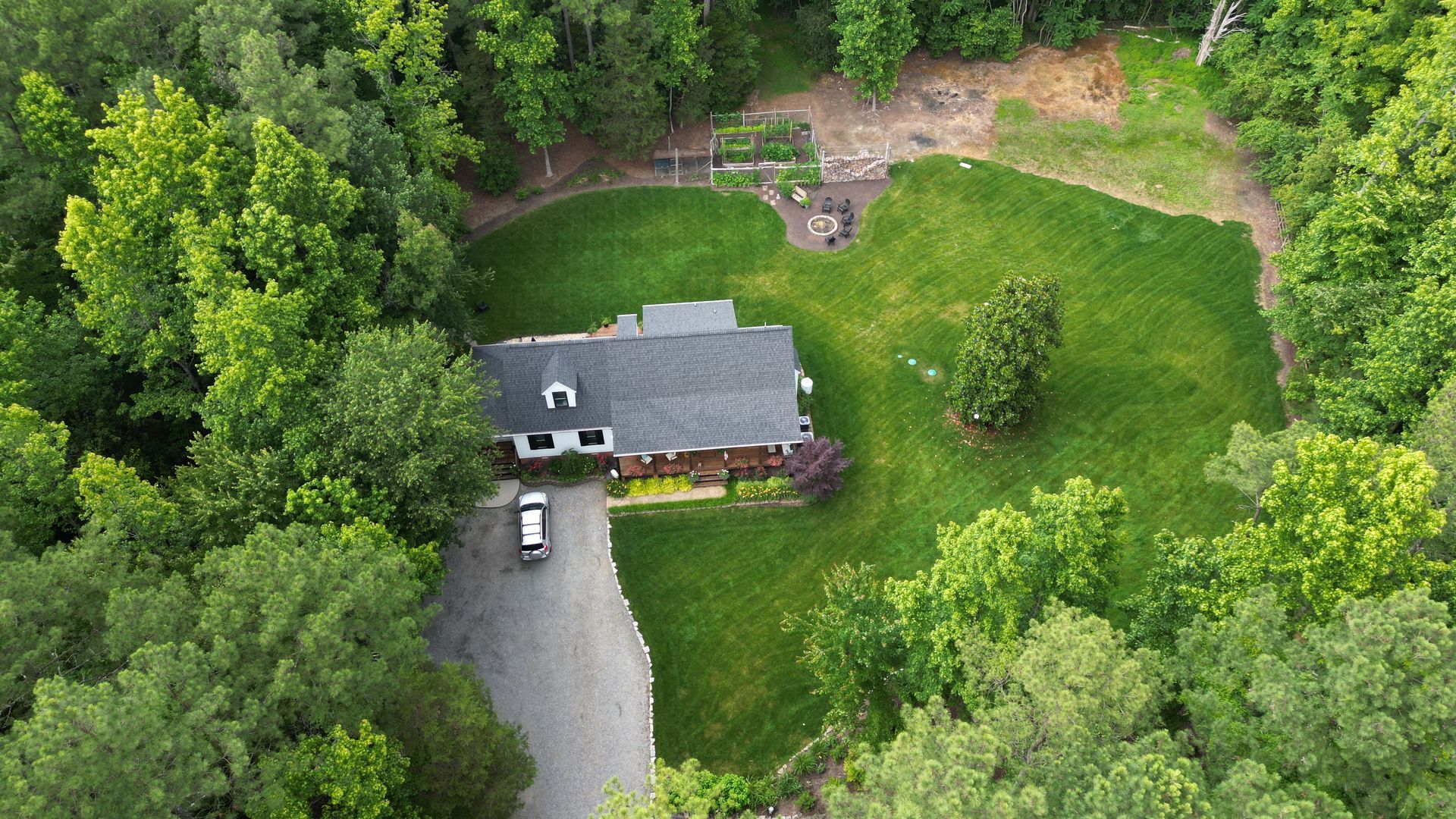 An aerial view of a house surrounded by trees and a driveway.