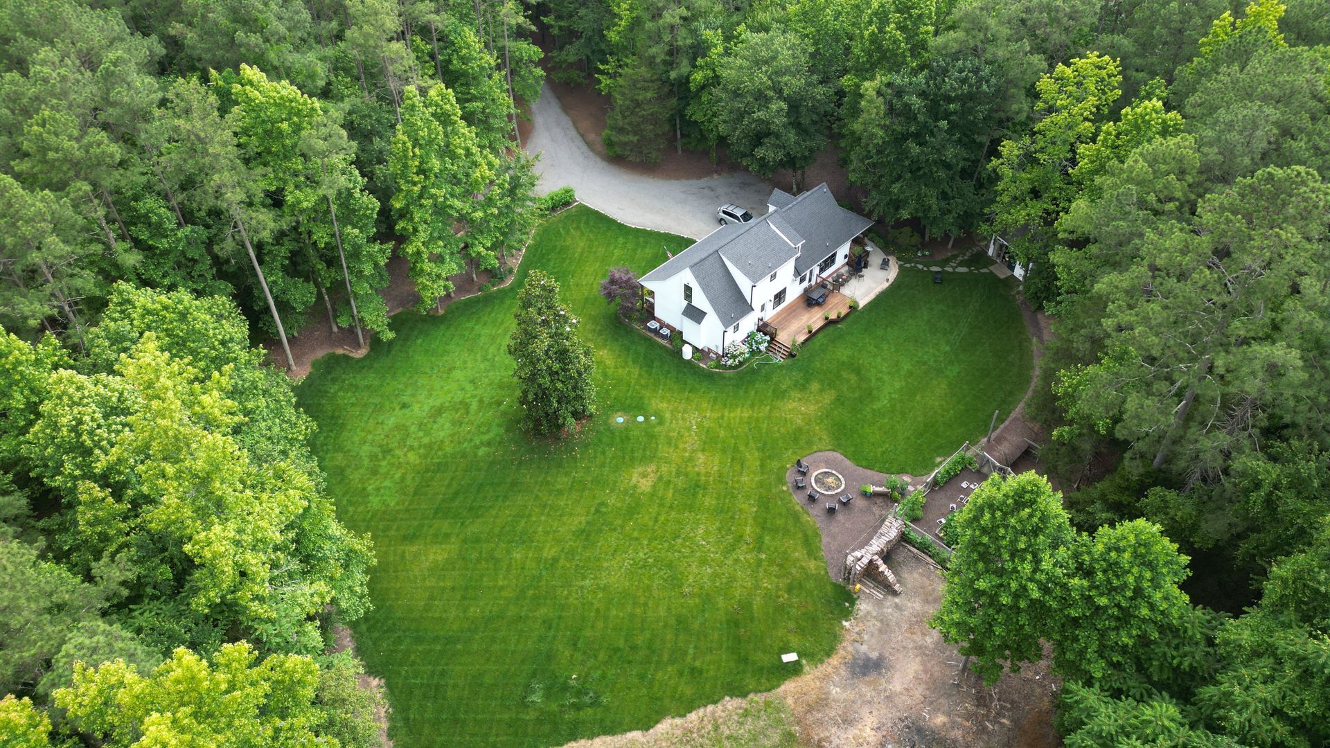 An aerial view of a house in the middle of a lush green forest.
