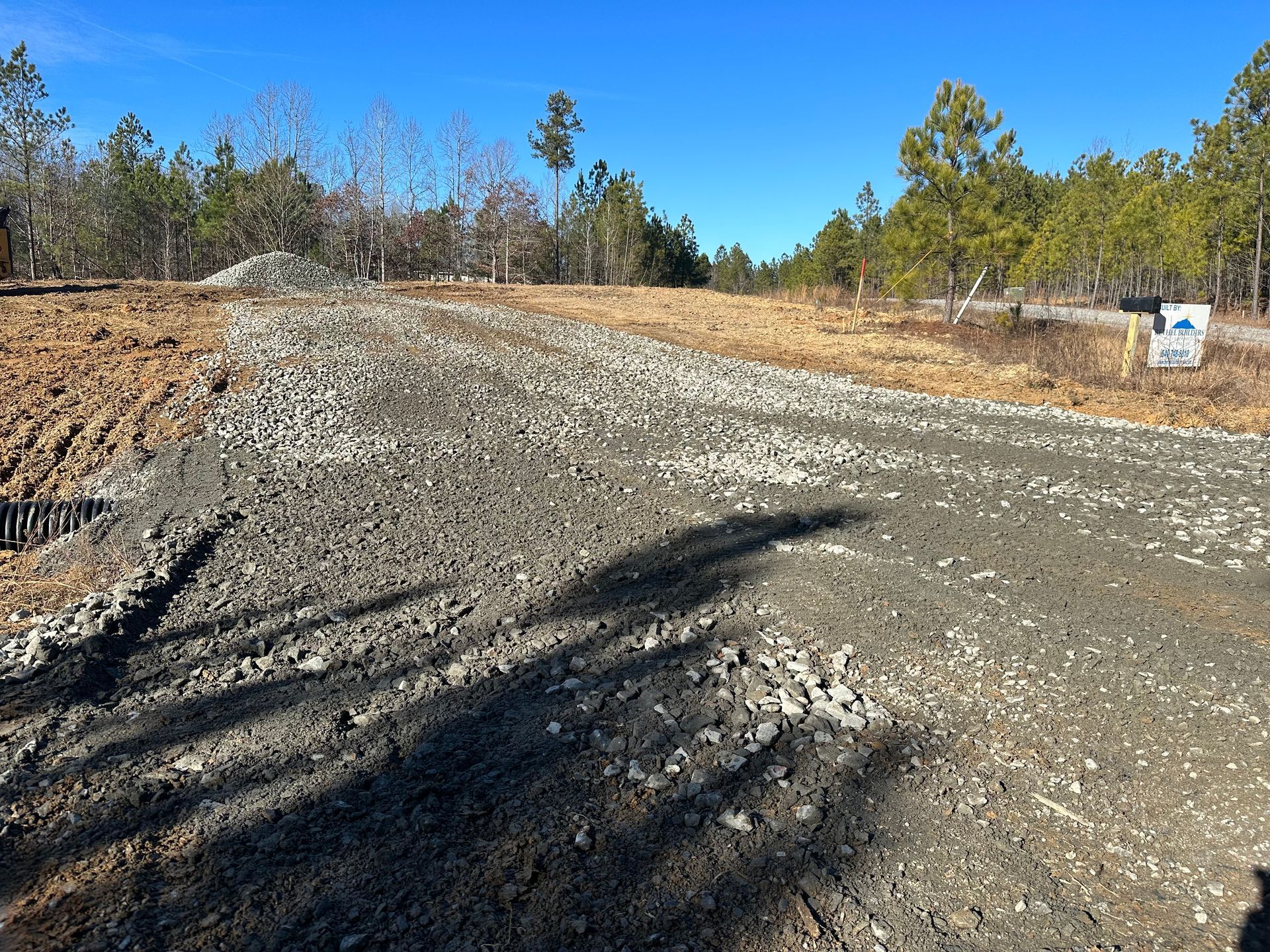 A dirt road in the middle of a field with trees in the background.