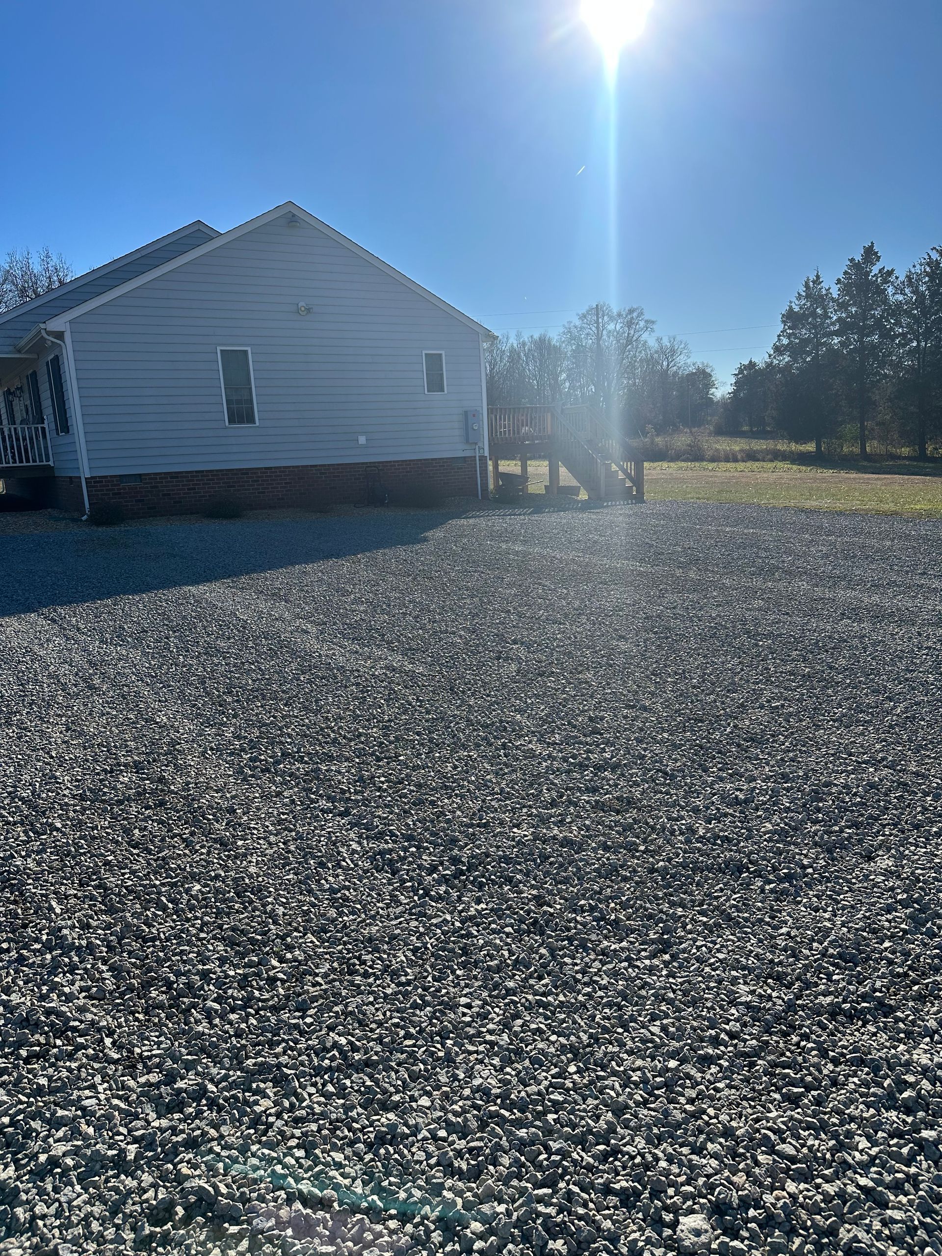 A white house is sitting on top of a gravel driveway.