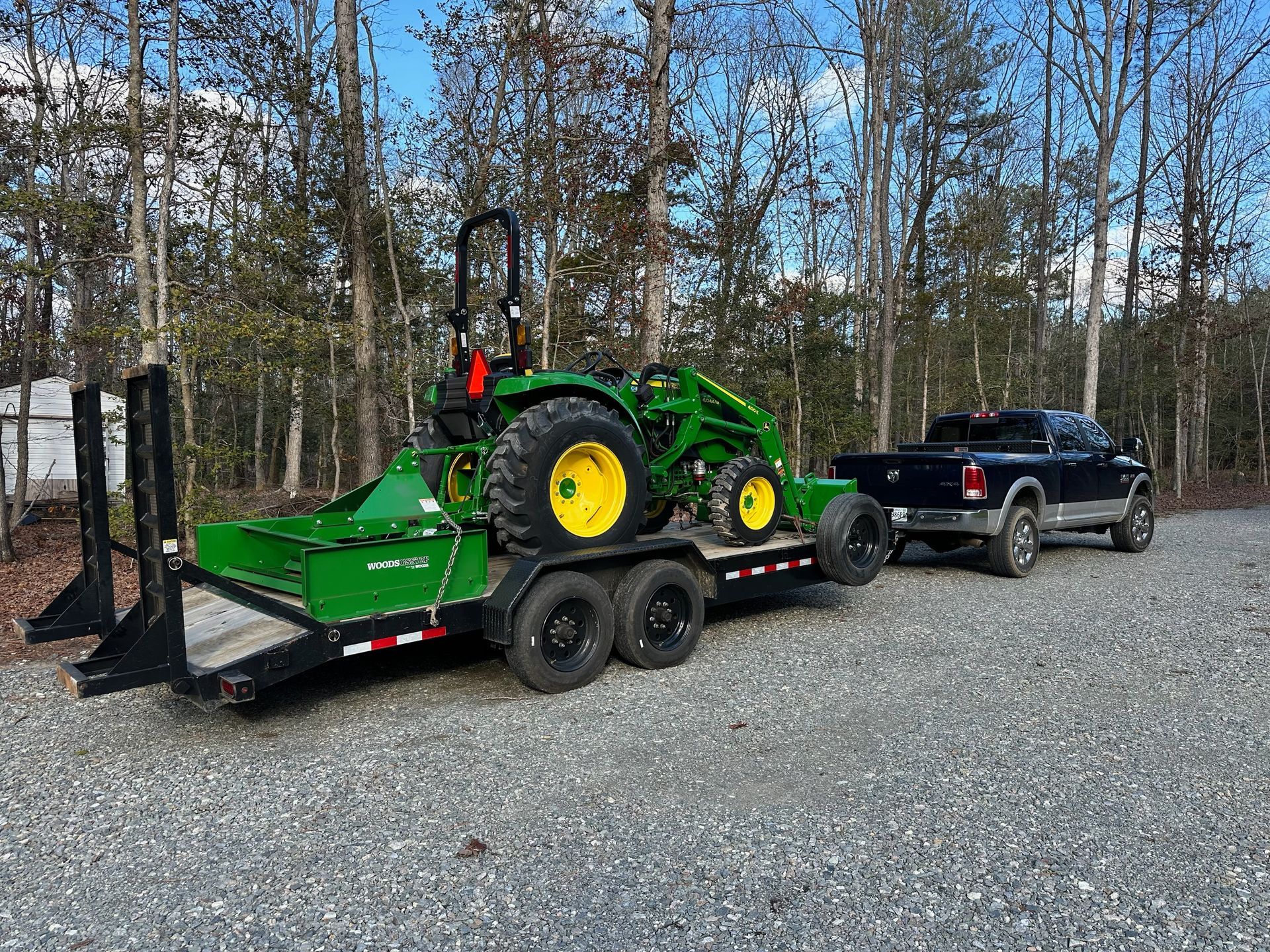 A tractor is being towed by a truck on a trailer.