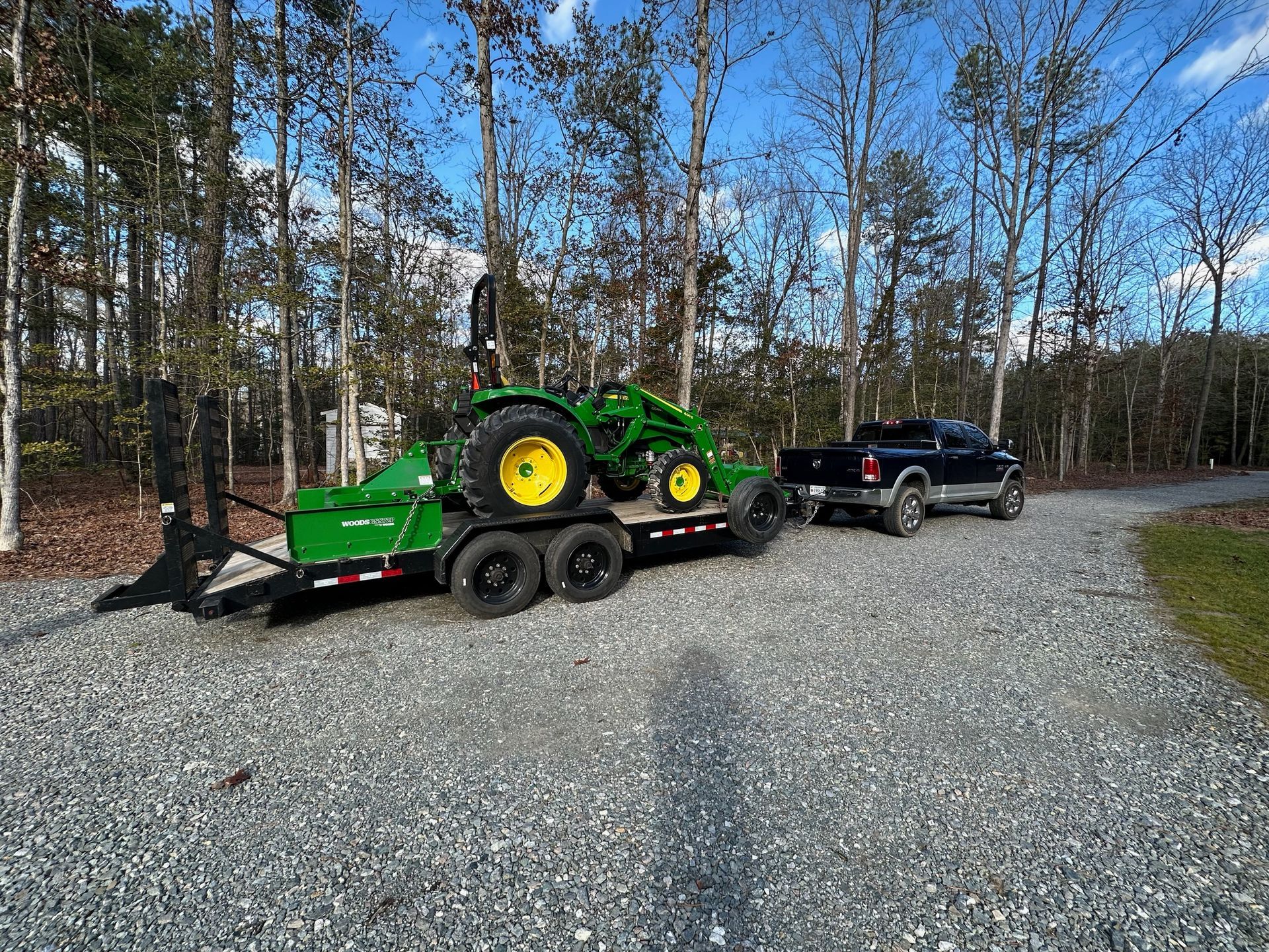 A tractor is being towed by a truck on a trailer.