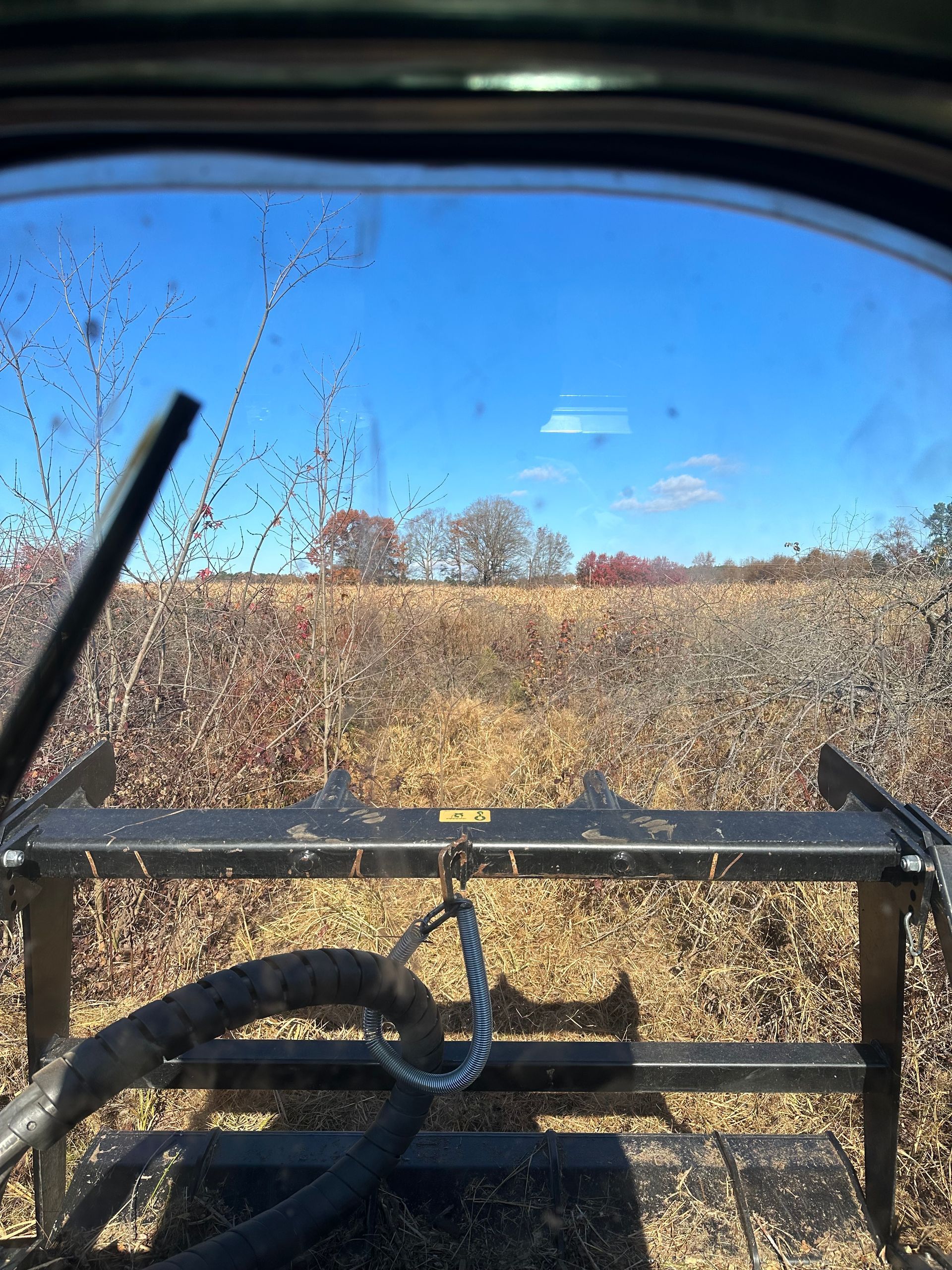 A view of a field through the windshield of a vehicle