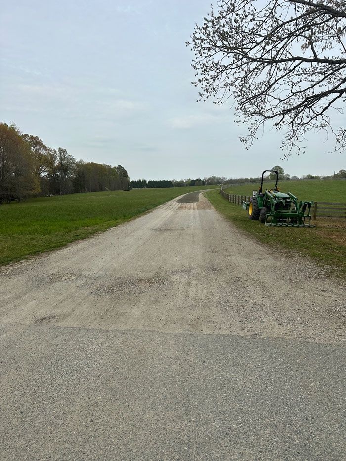 A tractor is parked on the side of a dirt road