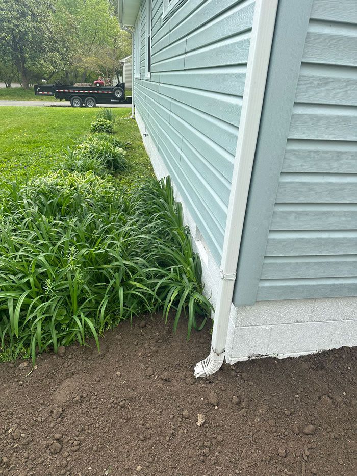 A house with blue siding and white trim is sitting on top of a dirt field.