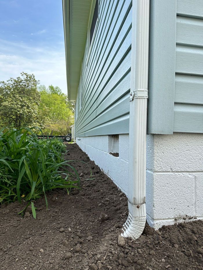 A white drainpipe is sitting on the side of a house.