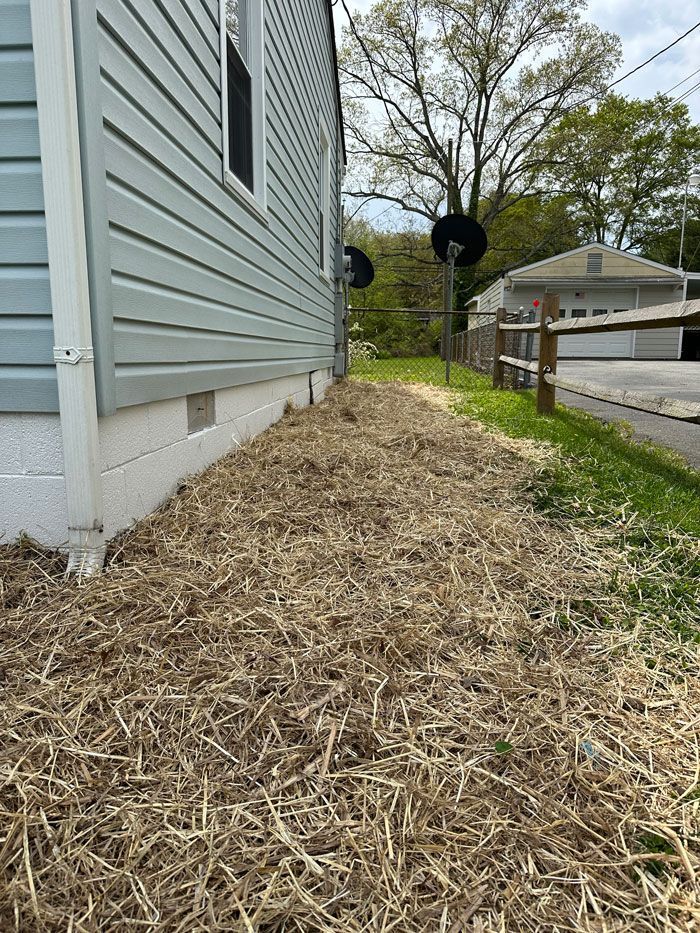 A house with a lot of hay on the side of it.