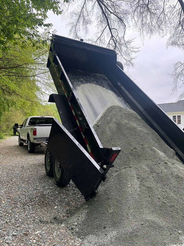 A dump truck is loading gravel into a trailer.