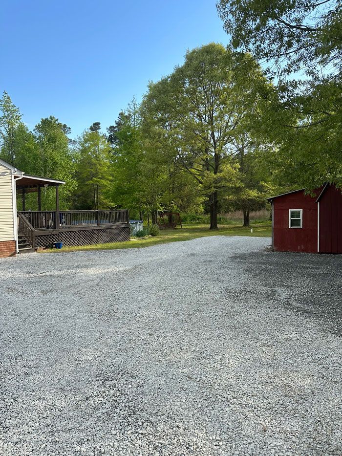 A gravel driveway leading to a house and a red shed.