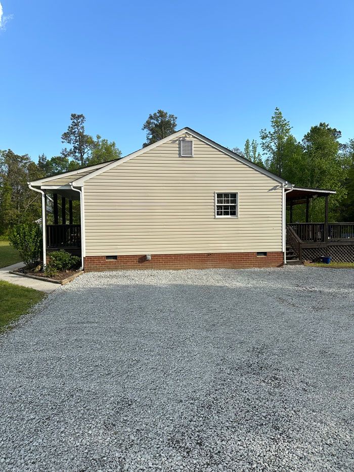 A small house with a gravel driveway in front of it.