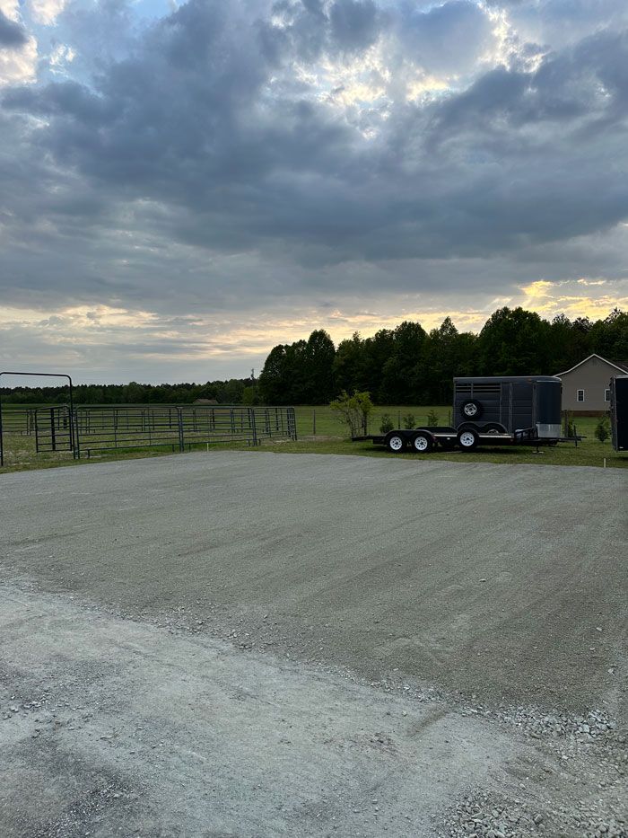 A trailer is parked in a gravel lot with a cloudy sky in the background.