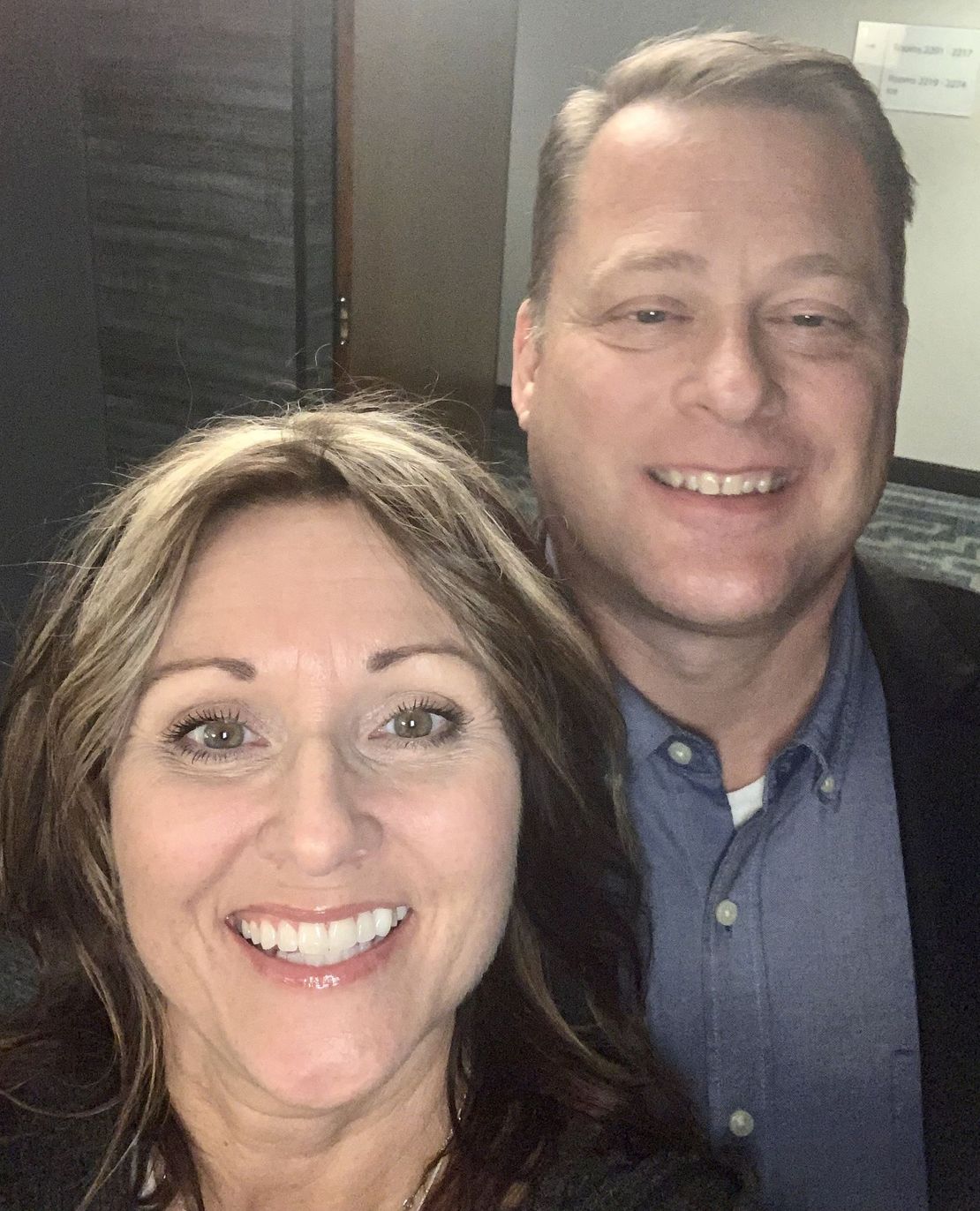 a man and a woman are smiling in front of a sign 