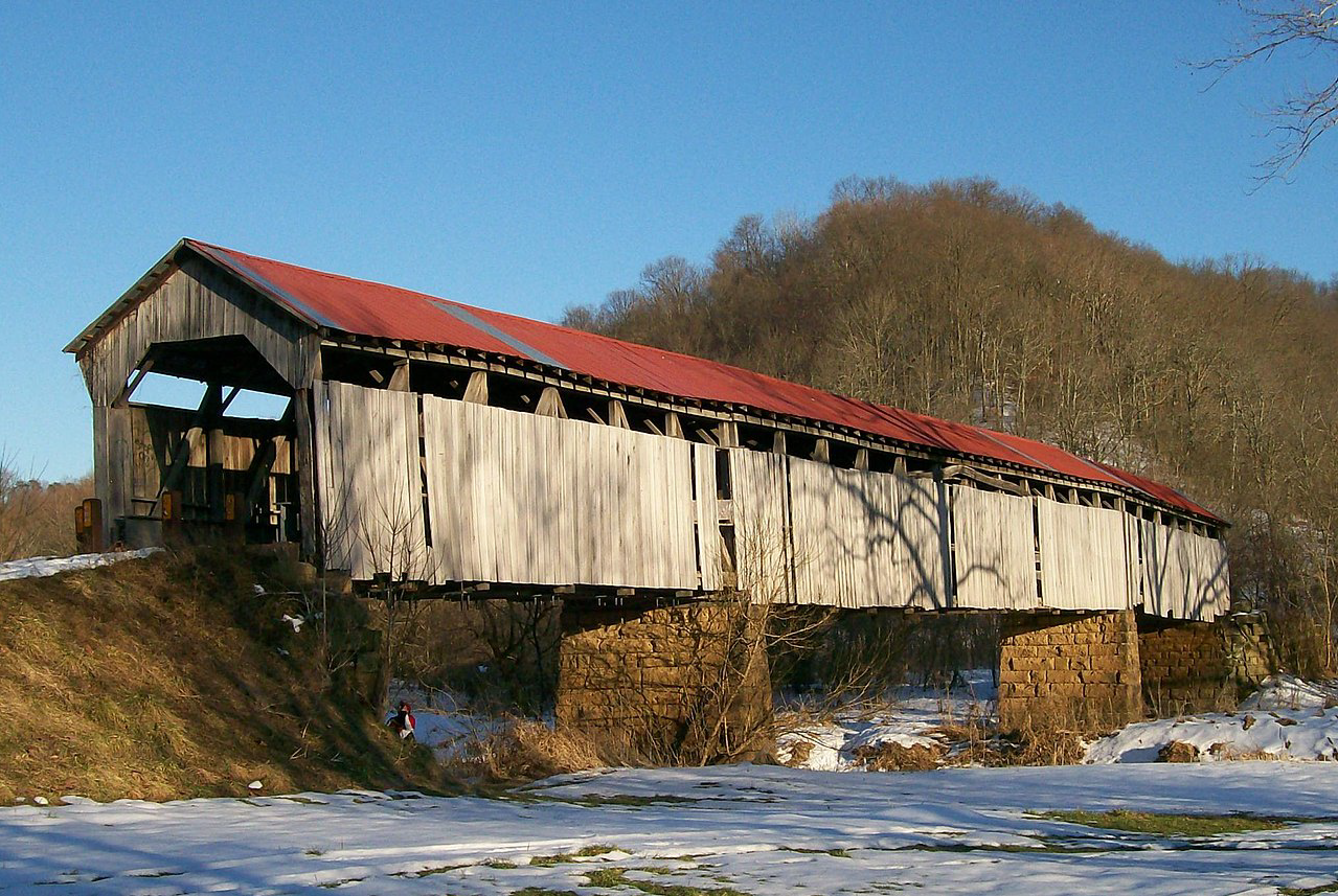 a wooden covered bridge with a red roof