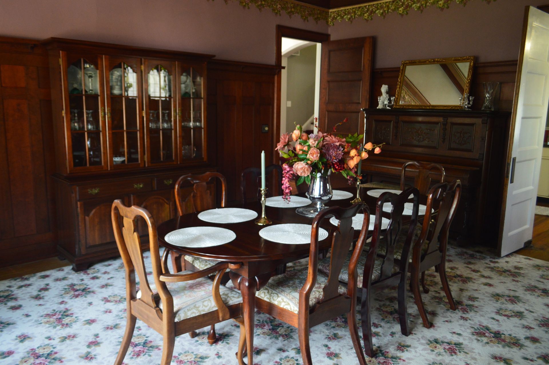 a dining room with a table and chairs and a vase of flowers