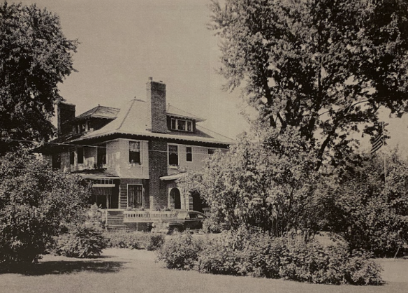 a black and white photo of a large brick house surrounded by trees