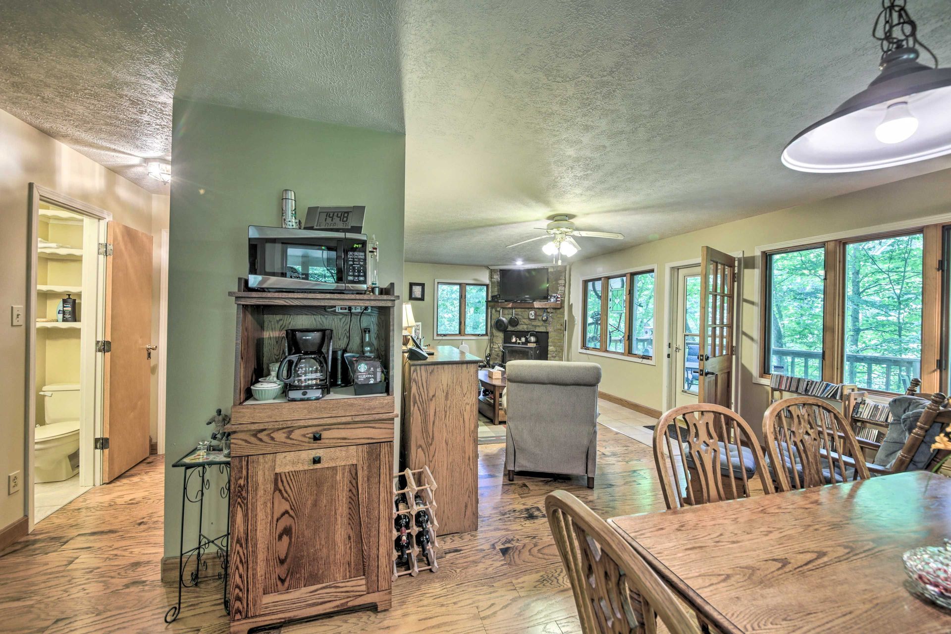 Interior view of a dining area, kitchen, and living room. Rustic wooden furniture, natural light.