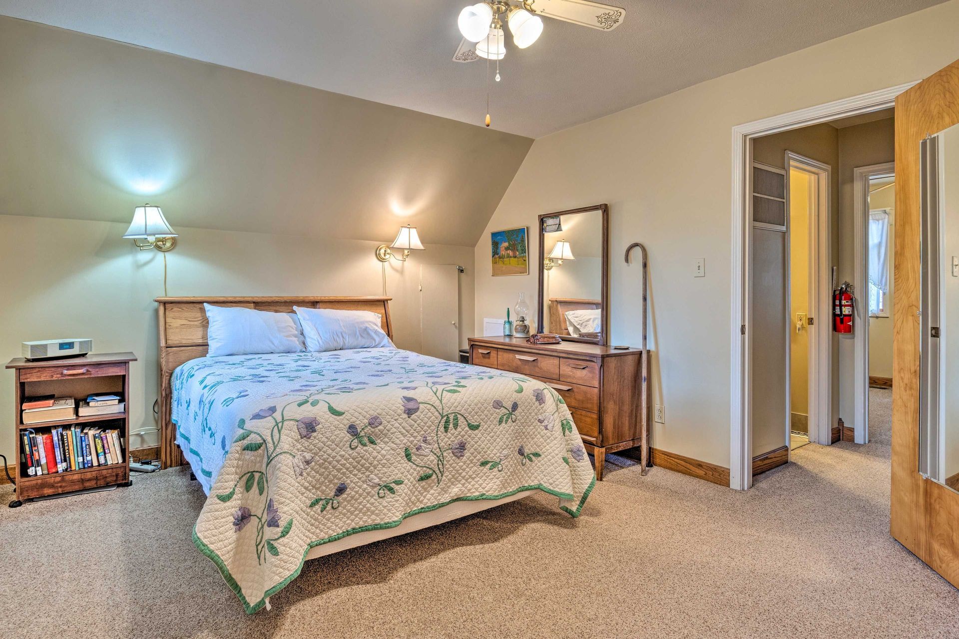 Bedroom with bed, dresser, and doorway to a hallway. Neutral colors, carpeted floors.
