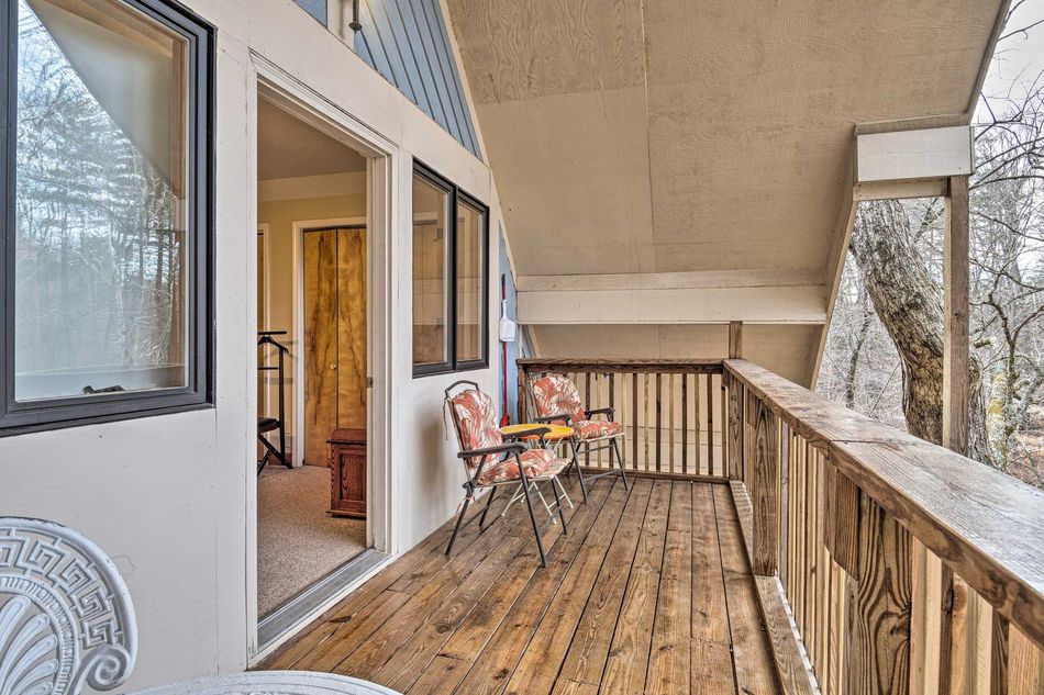 Balcony with wooden railing and two chairs, exterior of a house.