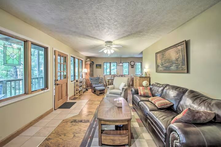 Living room with leather couch, windows, and wooden furnishings in a cabin.